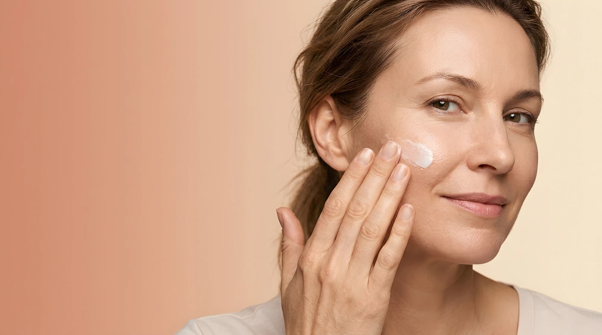 Woman applying a light cream to her cheek as part of a post-treatment skincare routine.