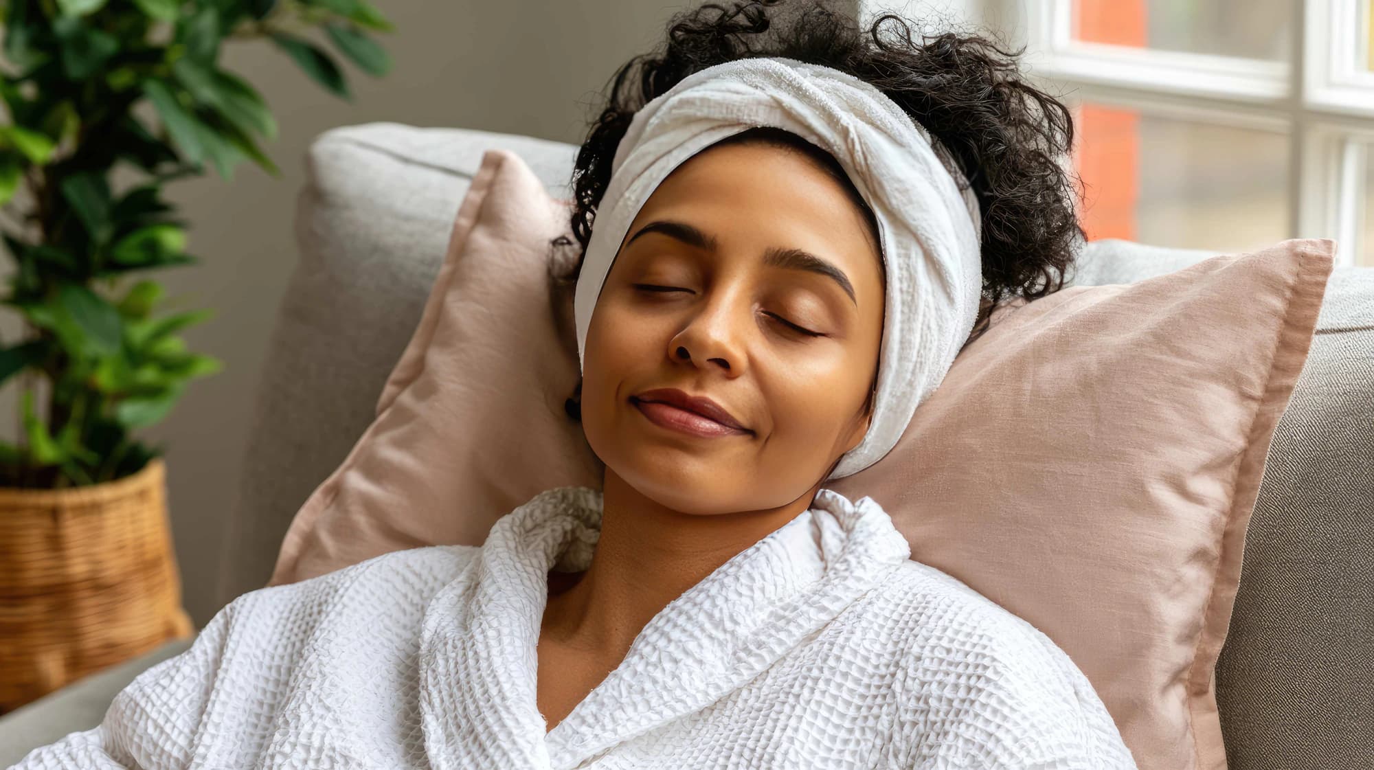 A woman resting with her eyes closed, wearing a headband and robe, in the hours after a treatment.