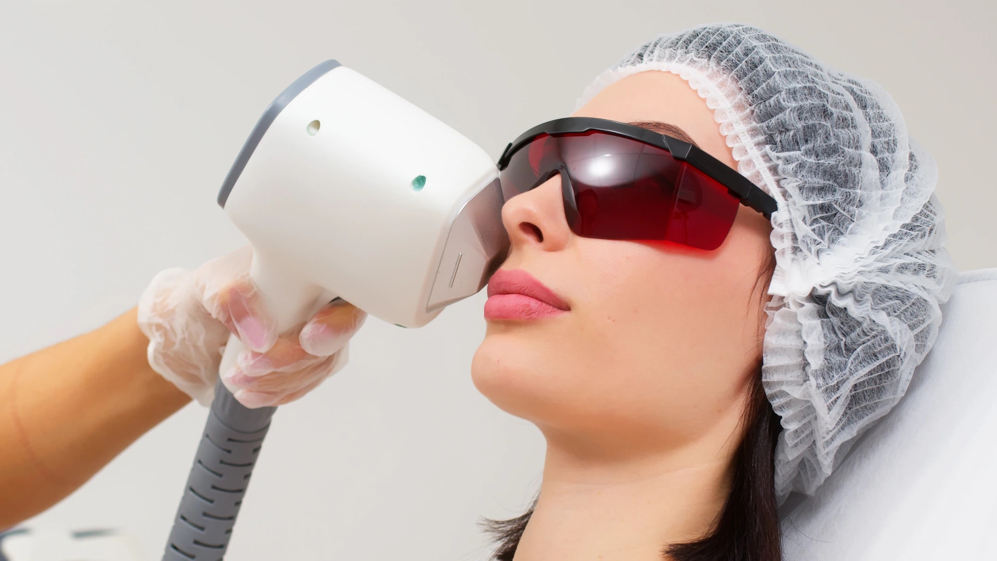 A client wearing protective eyewear receiving a light-based skin treatment.